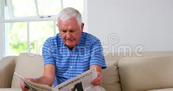成熟的男人在沙发上看报纸视频的预览图