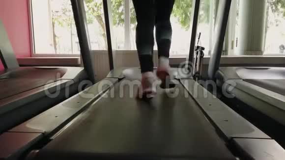 年轻女孩在运动健身房的跑步机上跑步视频的预览图