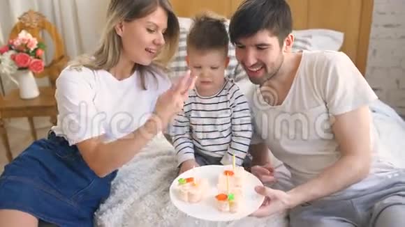 一家人笑着一起庆祝儿子的生日然后在蛋糕上点蜡烛视频的预览图