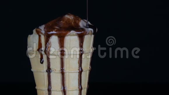 将巧克力糖浆酱汁倒入黑色背景的冰淇淋融化视频的预览图