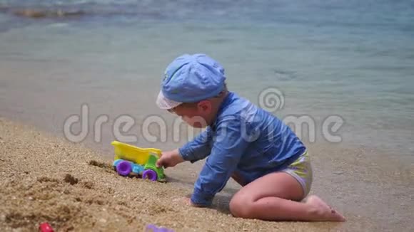 一个孩子在阳光明媚的热天在海滩上玩沙子和玩具视频的预览图