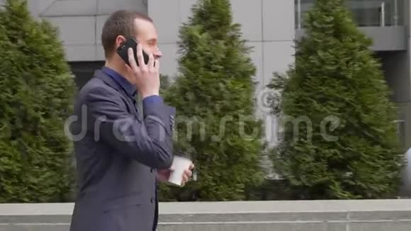 一位年轻的商人走在街上愉快地通过电话交流视频的预览图