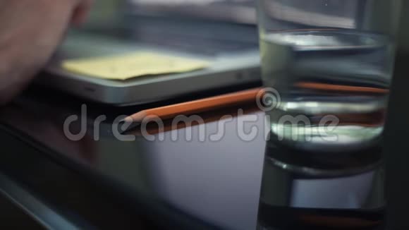 把铅笔贴在桌子上散焦物体玻璃水男性手在笔记本电脑上视频的预览图