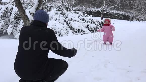 快乐的孩子在冬天的雪上向父亲走去4K视频的预览图