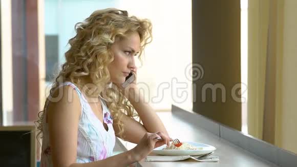 年轻女子在咖啡馆的餐桌上用手机聊天吃沙拉视频的预览图