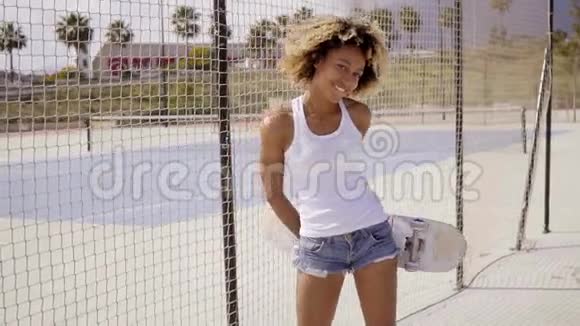 微笑着带着滑板的年轻黑人女人视频的预览图