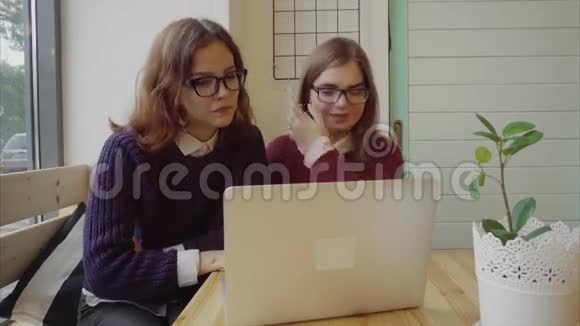 两个女孩通过网络聊天或在咖啡馆里视频聊天与朋友交谈视频的预览图