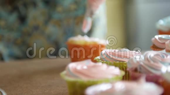 年轻女孩用奶油和浆果装饰纸杯蛋糕用烹饪袋糖果师为聚会制作多色纸杯蛋糕视频的预览图