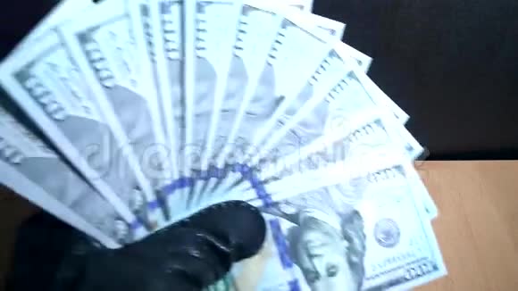 戴手套的人用放大镜检查一百美元的钞票视频的预览图
