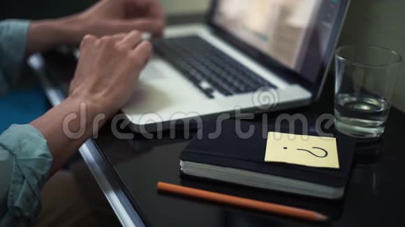 年轻人在家里滚动笔记本电脑书桌上有带问题标志的贴纸视频的预览图