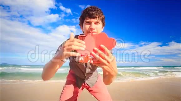 男子在冲浪沙滩上观看红色红心礼物视频的预览图