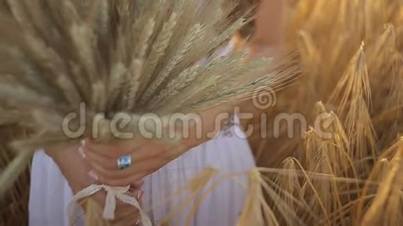日落时分一位年轻女子在田野里捧着一束麦穗慢动作视频的预览图