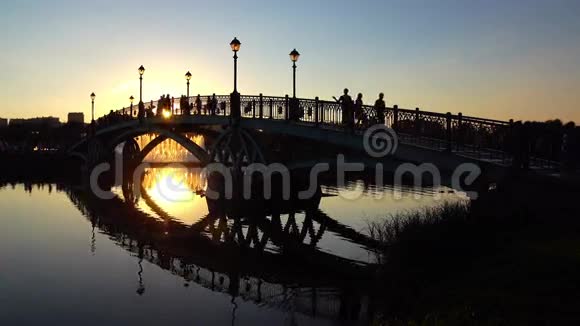 夏季日落时拱形公园桥和步行者的剪影4K视频视频的预览图