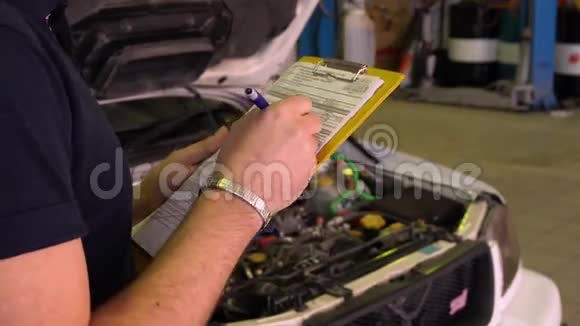 汽车修理工用钢笔在一辆汽车上装满了纸用来修理特写视频的预览图
