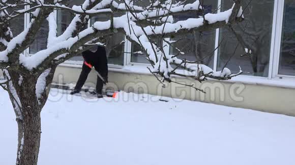 冬天看门人从家附近的人行道上清扫积雪4K视频的预览图