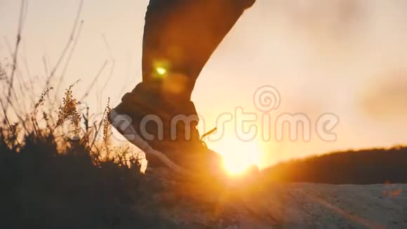 徒步旅行者在日落时在岩石上散步穿着长途跋涉的靴子的腿沿着山脊走视频的预览图