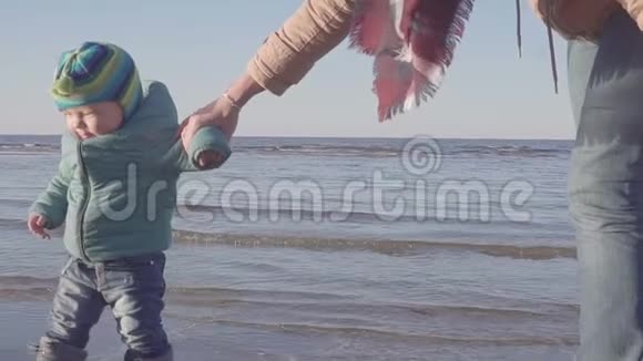 妈妈带着一个小孩沿着春天的海滩散步视频的预览图