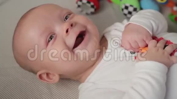 一个可爱的小宝宝正看着相机在一张白色的床单上很开心视频的预览图