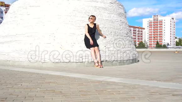 时尚时尚的年轻女模特戴着太阳镜穿着一件黑色连衣裙在户外视频的预览图