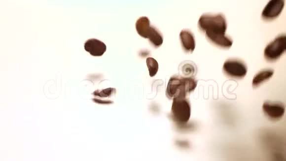 掉落的烤咖啡豆覆盖白色背景超级慢镜头视频的预览图