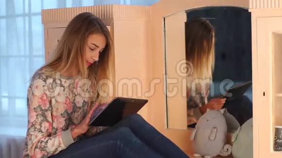 年轻漂亮的少女坐在客厅的马桶上用平板电脑和朋友聊天很有趣视频的预览图