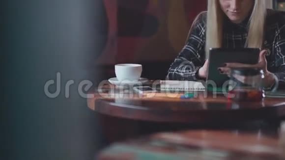 现代生活方式可爱的女孩和一个平板电脑坐在桌子旁的咖啡馆视频的预览图