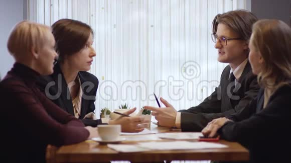 四个人一起工作在咖啡馆里讨论一份合同三个女人和一家餐馆里的男人视频的预览图