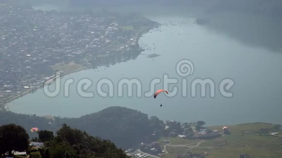 在尼泊尔波哈拉市的普瓦湖上空飞行的滑翔伞视频的预览图