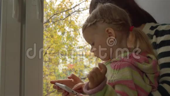 秋日母女俩在智能手机的窗台上玩视频的预览图