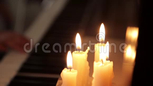 在蜡烛的灯光下特写女性双手在黑暗中弹钢琴视频的预览图