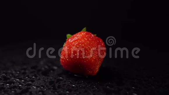 一个成熟的草莓和水滴在黑色的背景上旋转视频的预览图