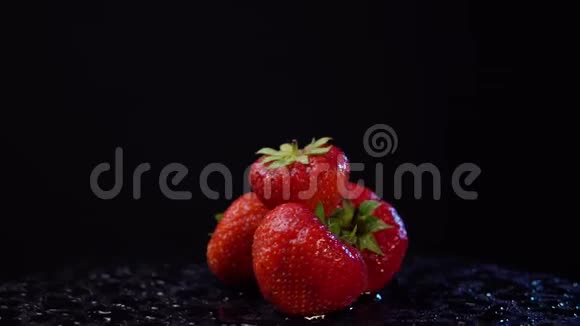 一个成熟的草莓和水滴在黑色的背景上旋转视频的预览图