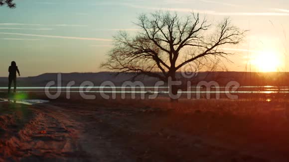 剪影人在日落时沿着道路奔跑独自站在树上剪影在大自然中奔跑的运动青年视频的预览图