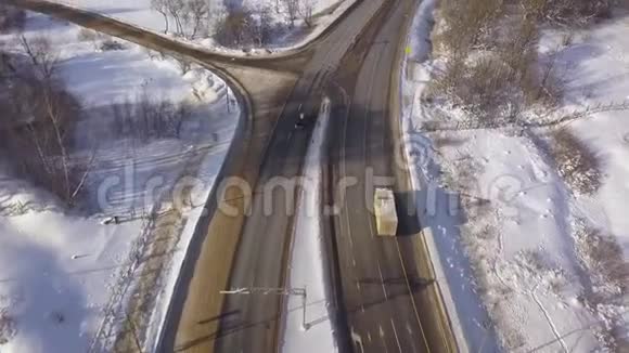 汽车和货运卡车从上面的飞行无人机在冬季公路上行驶雪道上的空中观景车交通视频的预览图
