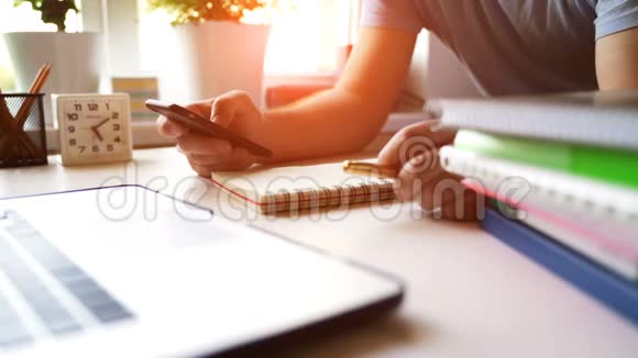 在清晨的阳光下商人在办公室里使用智能手机和笔记本电脑视频的预览图