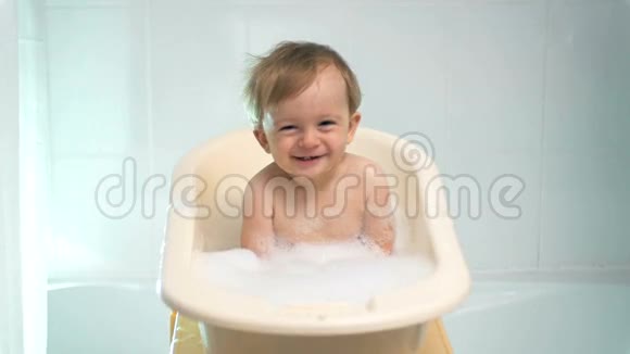 慢镜头可爱的笑着的小男孩坐在浴缸里视频的预览图
