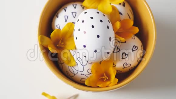 白色背景上的黄色杯子和复活节彩蛋黄色杯子里的复活节鸡蛋白色鸡蛋黑色图案美丽美丽视频的预览图