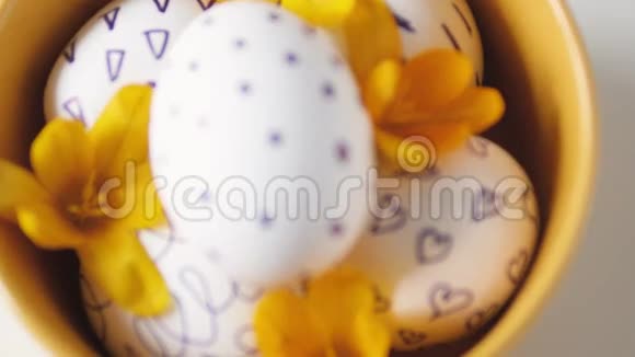 白色背景上的黄色杯子和复活节彩蛋黄色杯子里的复活节鸡蛋白色鸡蛋黑色图案美丽美丽视频的预览图