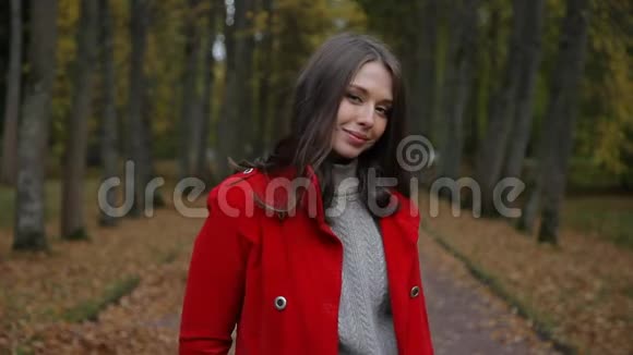 美丽的白种人女人穿着红色外套在秋天的森林里用纸出售标语牌视频的预览图
