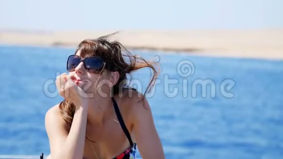 夏天大海肖像美丽的年轻黑发女人穿着泳衣和太阳镜站在甲板上视频的预览图