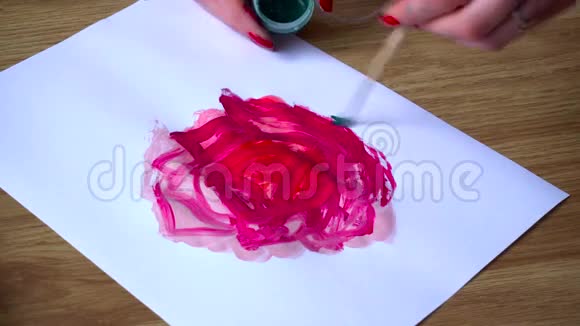 接近艺术家在白纸上画一朵带有绿叶的抽象红花视频的预览图