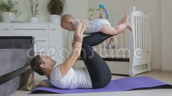 年轻的母亲和她的小男孩一起在客厅的健身垫上锻炼视频的预览图