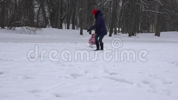 白种人女人用雪橇拉着婴儿穿过雪堆4K视频的预览图