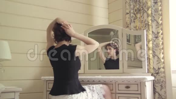 美丽的年轻女孩穿着黑色的裙子坐在一面老式镜子前镜子里有三面镜子视频的预览图
