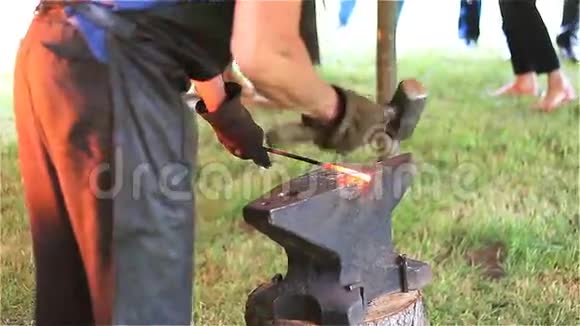 一个经验丰富的铁匠在铁匠铺里加热金属并在铁砧上锻造熔化的金属视频的预览图