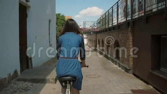 夏天一个穿着连衣裙的女孩骑着一辆自行车花篮在街上慢的莫稳定的镜头视频的预览图