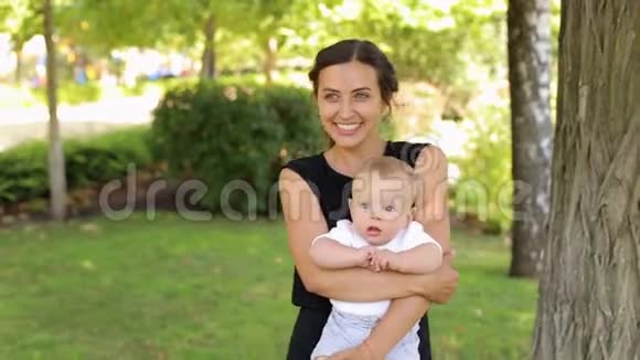 夏天一位年轻快乐的母亲和她刚出生的儿子在公园里散步视频的预览图