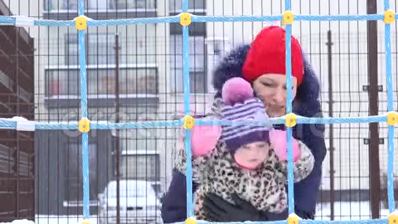 活跃的女人和女婴一起在院子里享受降雪的暴风雪4K视频的预览图