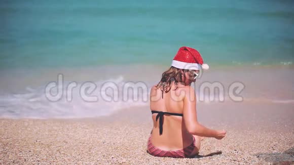 圣诞海滩度假圣诞老人帽子女人坐在沙滩上的天堂旅行目的地放松视频的预览图