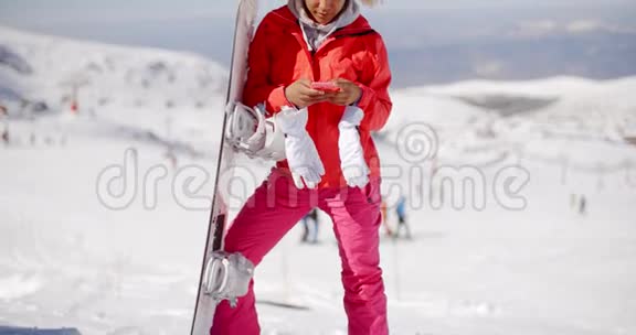 微笑滑雪者在斜坡顶部检查电话视频的预览图